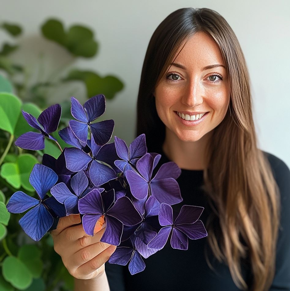 A woman holding a vibrant purple Butterfly Plant (Oxalis triangularis) in her hand.