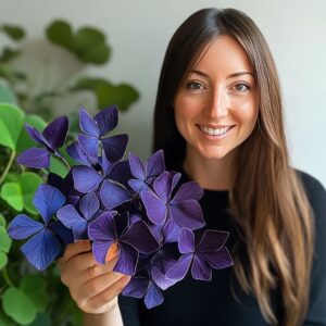 A woman holding a vibrant purple Butterfly Plant (Oxalis triangularis) in her hand.